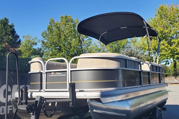 Sun Tracker Party Barge 18 DLX 2025 Sun Tracker Party Barge 18 DLX pontoon boat with canopy, parked outdoors.