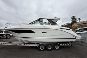 Sea Ray Sundancer 320 2026 Sea Ray Sundancer 320 boat on trailer, side view, overcast sky.