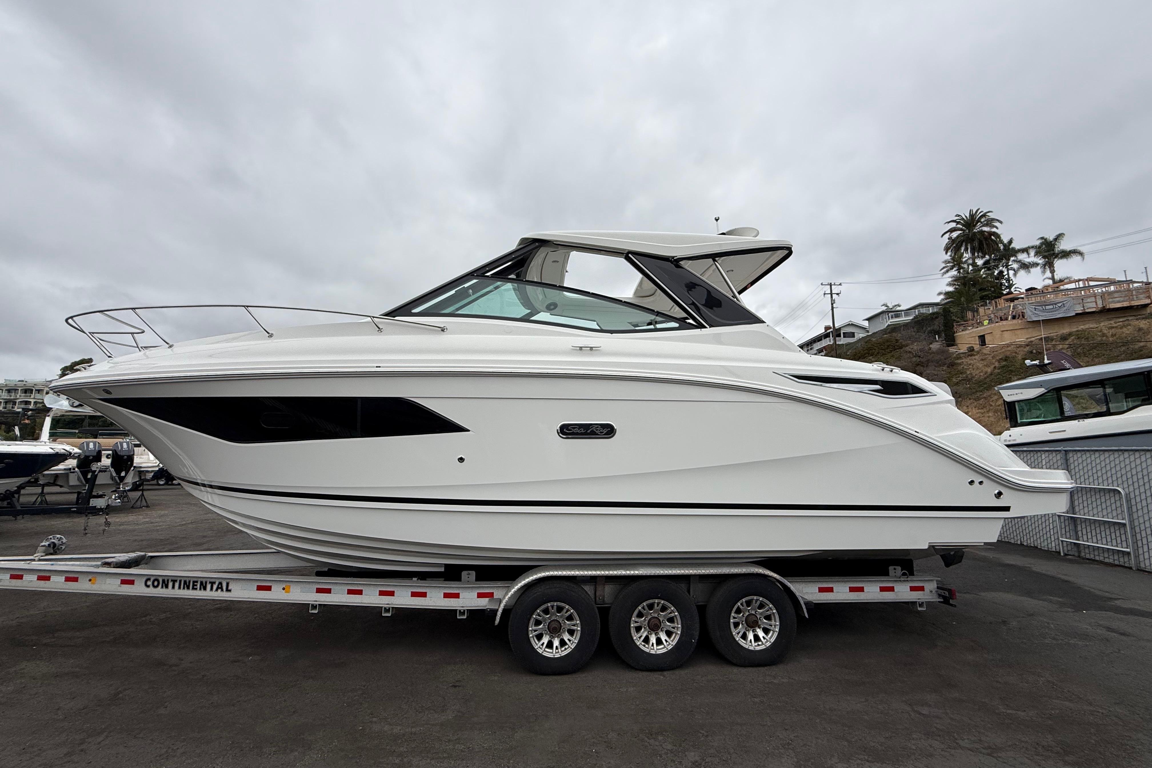Sea Ray Sundancer 320 2026 Sea Ray Sundancer 320 boat on trailer, side view, overcast sky.