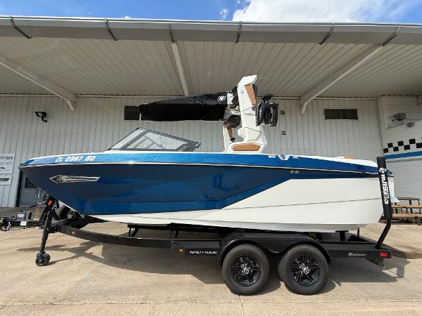 Nautique G21 2024 Nautique G21 boat on trailer, blue and white design, parked outdoors.