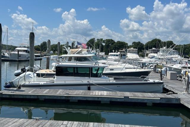 Axopar 28 2019 Axopar 28 boat docked at a marina under a partly cloudy sky.