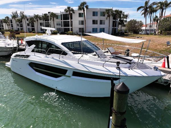 Cruisers Yachts 42 Cantius 2019 Cruisers Yachts 42 Cantius docked near waterfront apartments, surrounded by palm trees.