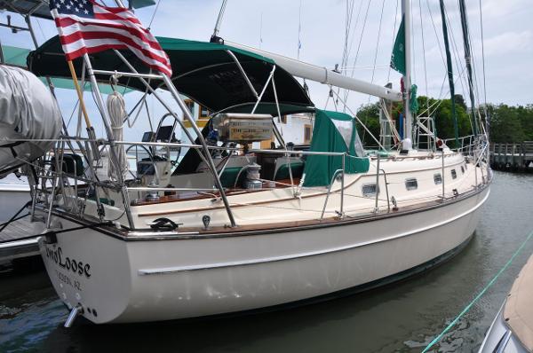 Island Packet 45 1998 Island Packet 45 sailboat docked, featuring green canvas covers and American flag.