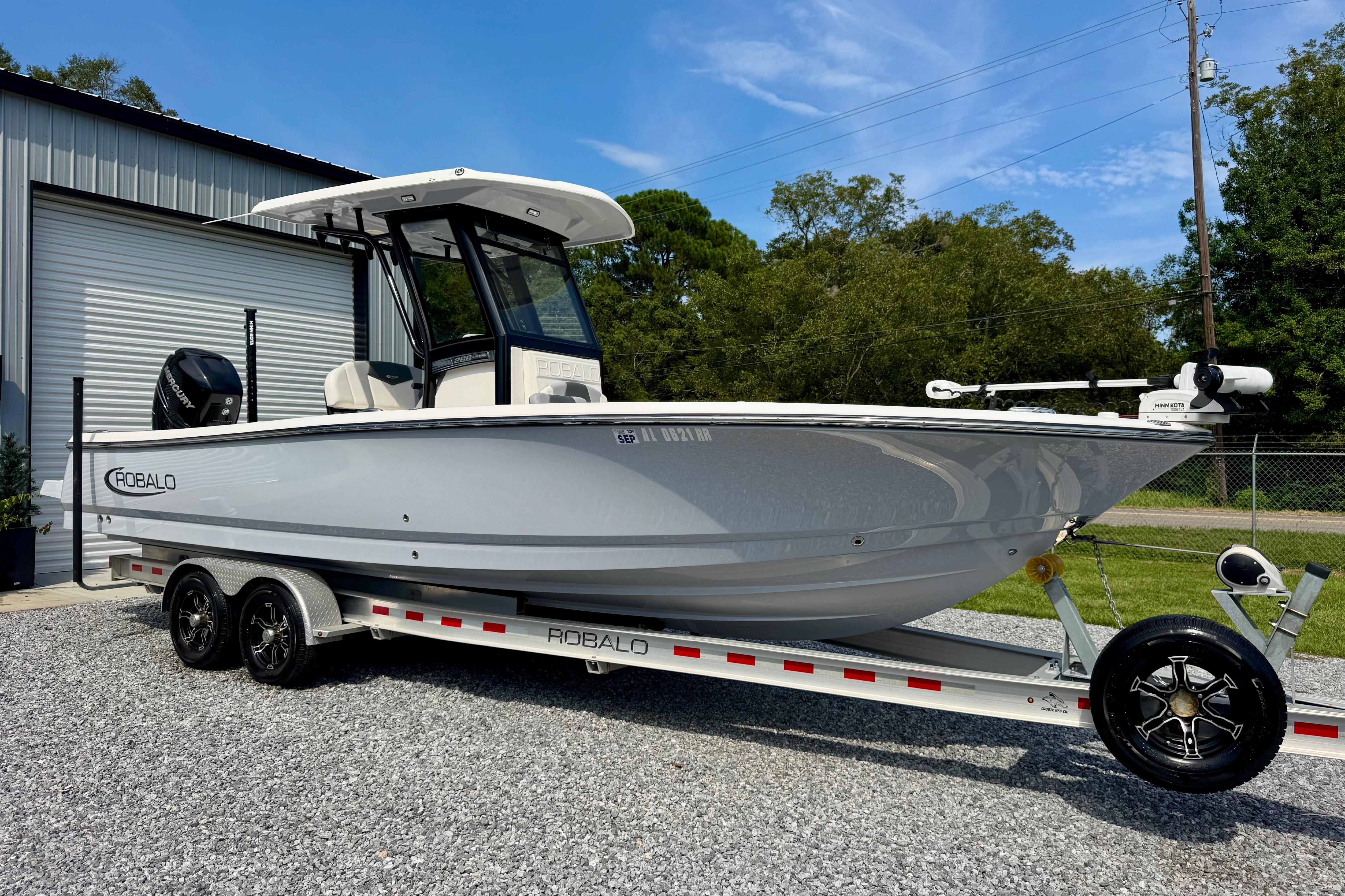 Robalo 266 Cayman 2022 Robalo 266 Cayman boat on trailer, parked outdoors near a garage.