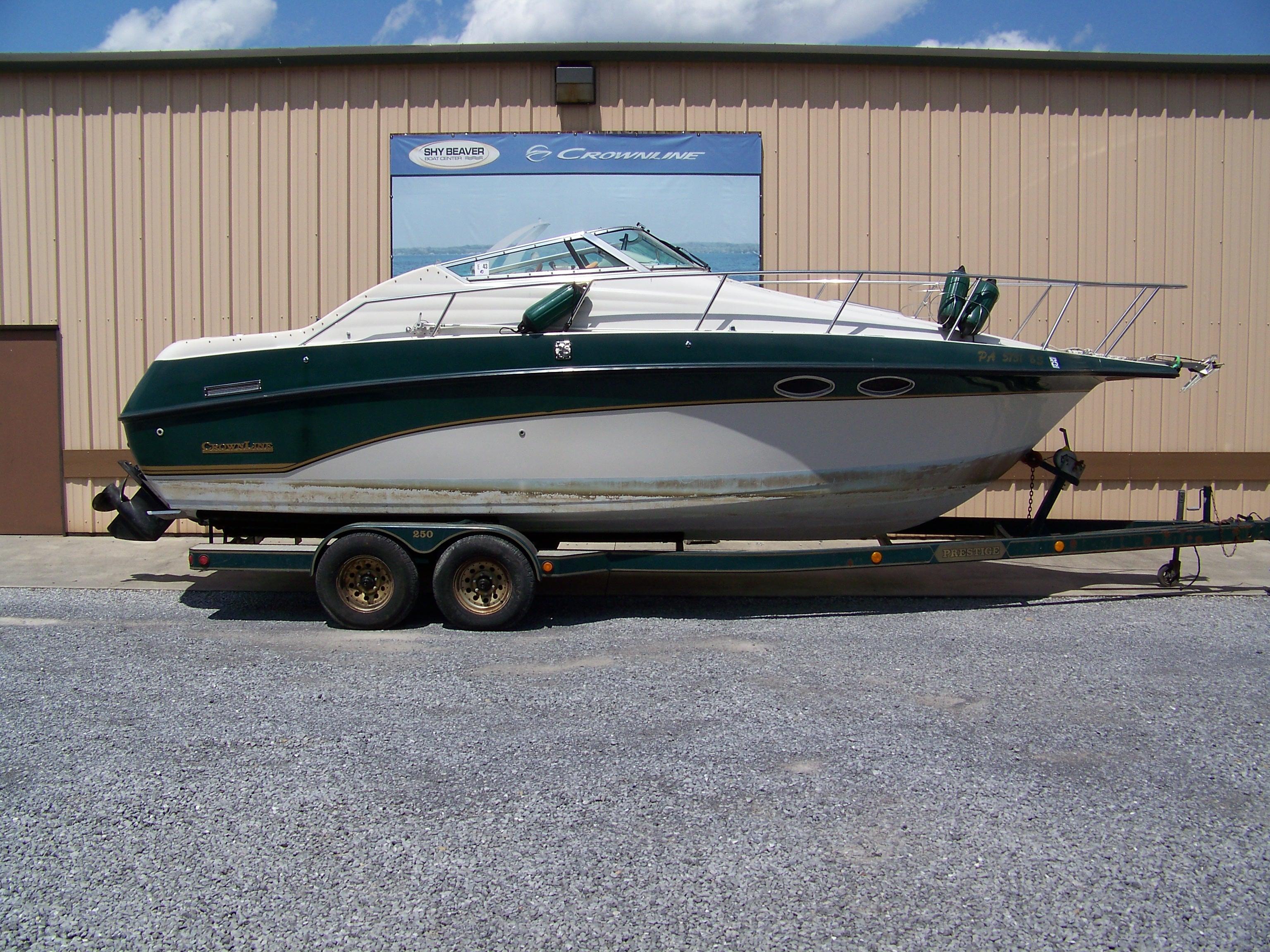 Crownline 250 CR 1996 Crownline 250 CR boat on trailer, parked outside a beige building under a blue sky.