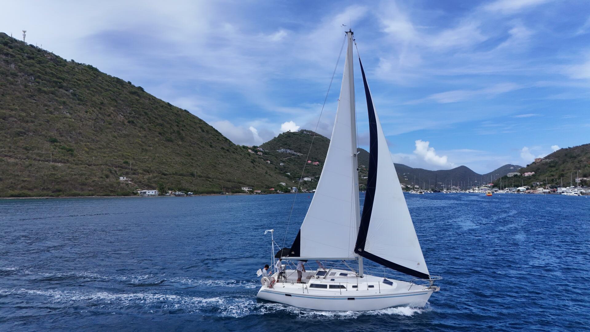 Catalina 32 Sailboat Catalina 32 (1994) cruising in scenic coastal waters with hills in the background.