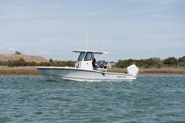 Blackfin 262 HB 2025 Blackfin 262 HB boat cruising on calm waters near a shoreline.