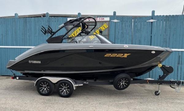 Yamaha Boats 222XD 2025 Yamaha Boats 222XD on trailer, sleek black design, parked by blue fence.