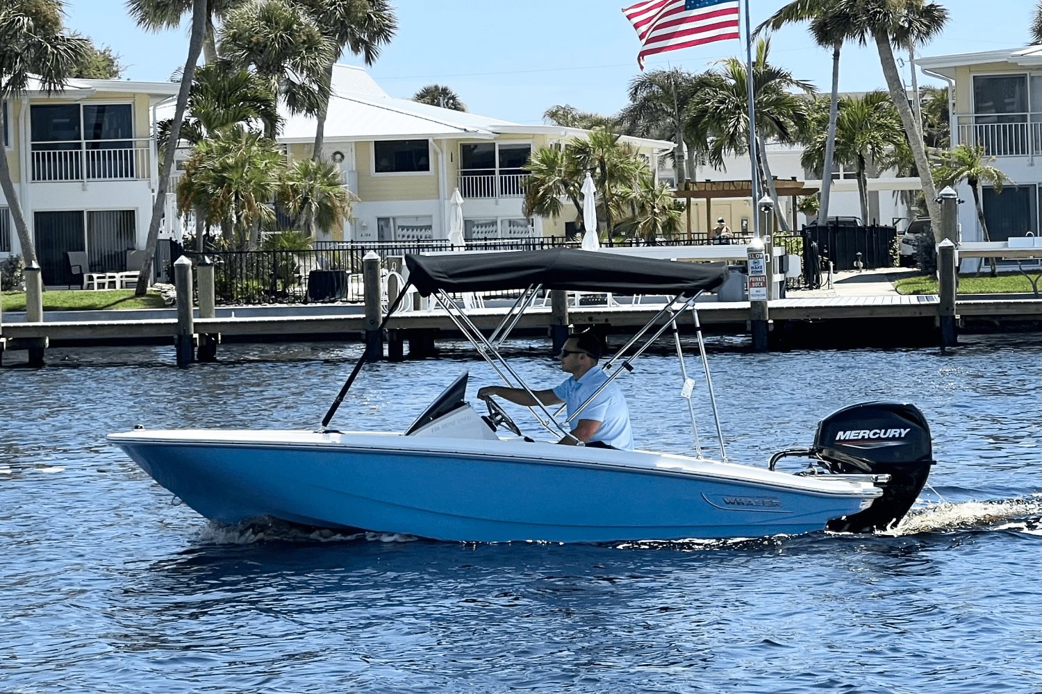 Boston Whaler 130 Super Sport 2026 Boston Whaler 130 Super Sport boat cruising on a sunny day near waterfront homes.