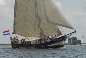 Custom Klipper Hoop op Zegen Custom Klipper Hoop op Zegen sailing with Dutch flag, 2002 model, on a calm waterway.