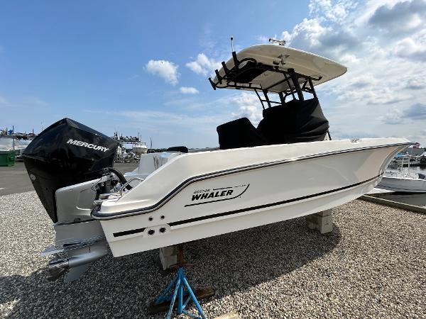 Boston Whaler 230 Outrage 2024 Boston Whaler 230 Outrage boat with Mercury engine on gravel lot.