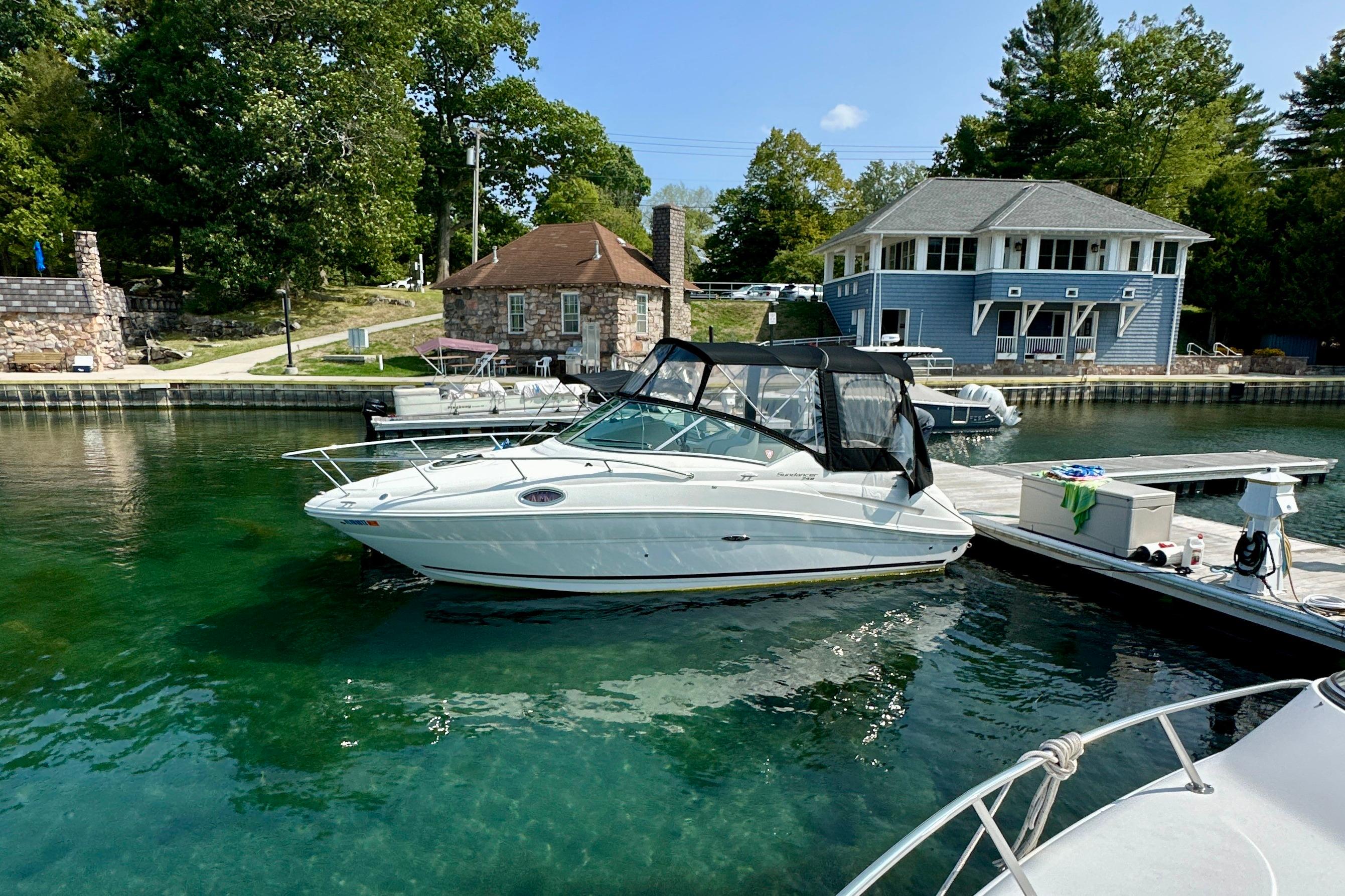 Sea Ray 240 Sundancer 2012 Sea Ray 240 Sundancer docked in clear water near rustic buildings.