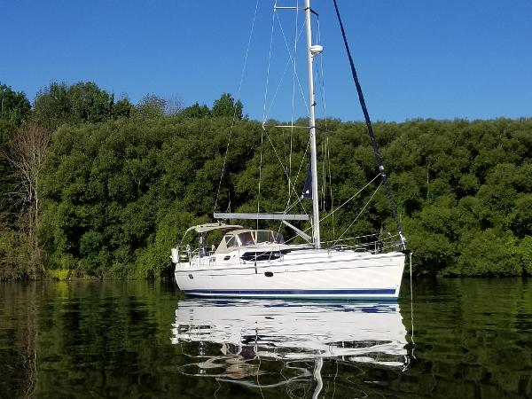 Hunter 45 Deck Salon 2010 Hunter 45 Deck Salon sailboat on calm water, surrounded by lush greenery.