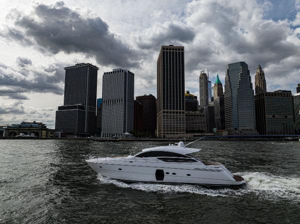 Pershing 64 MOTOR YACHT Pershing 64 Motor Yacht cruising near city skyline under cloudy skies, 2013 model.