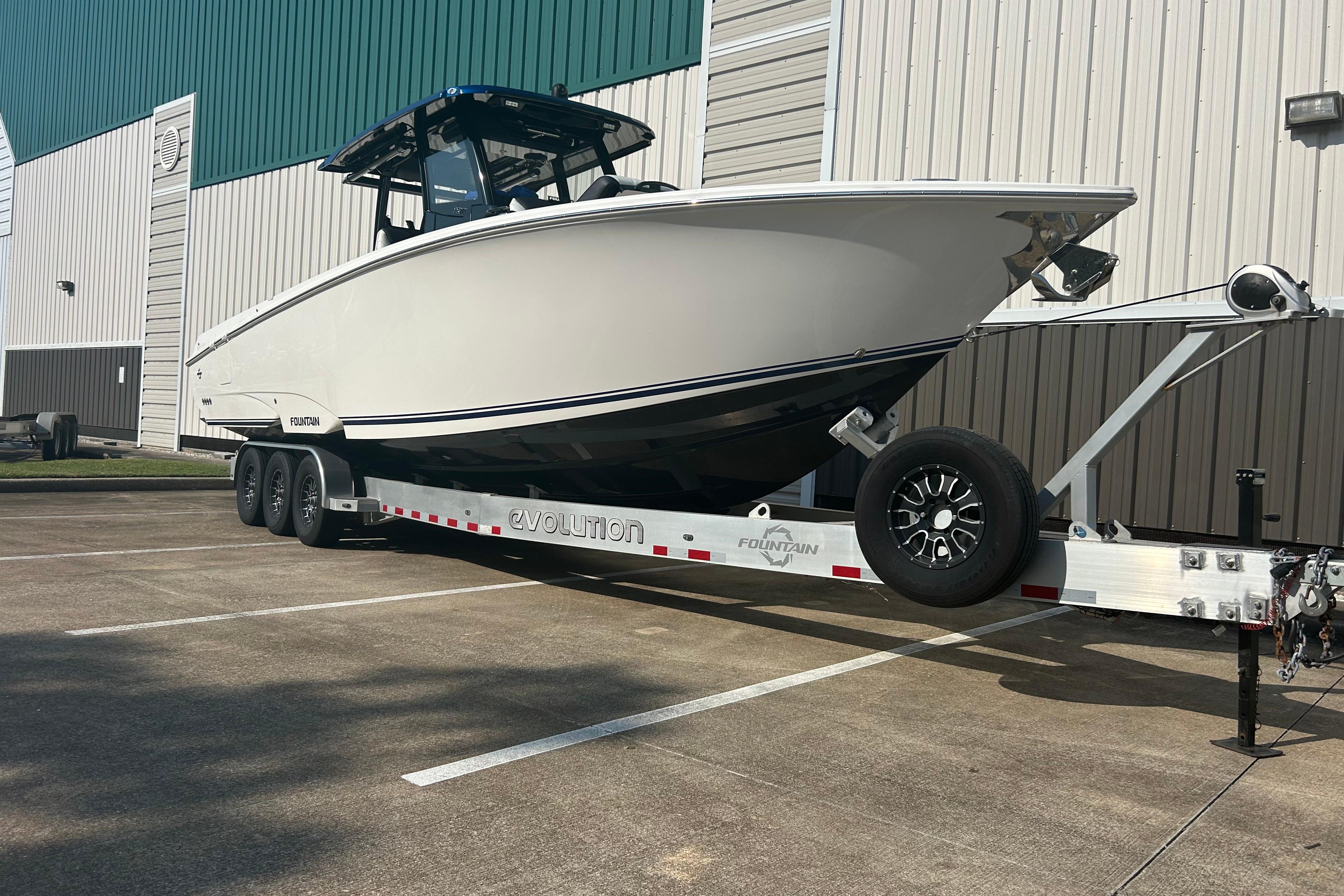 Fountain 32 NX 2025 Fountain 32 NX boat on trailer, parked outside a large building.