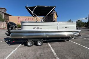 Sun Tracker Party Barge 22 DLX 2026 Sun Tracker Party Barge 22 DLX pontoon boat parked in a lot under clear skies.
