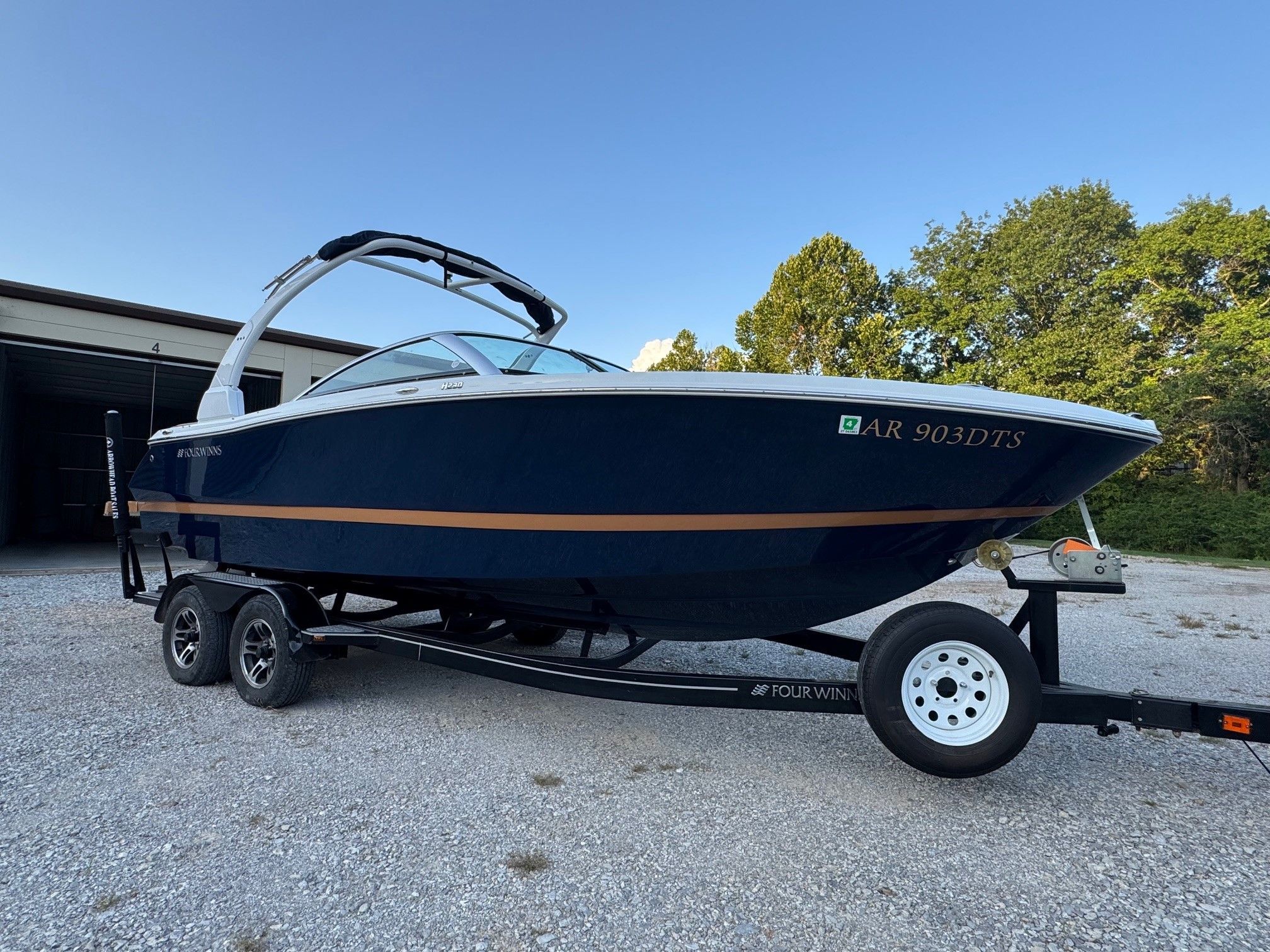 Four Winns H230 2020 Four Winns H230 boat on trailer, parked outdoors, clear sky background.