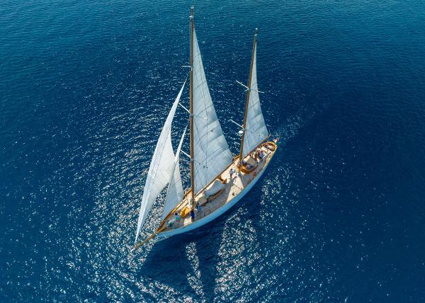 Custom VERONESE ketch Aerial view of 1947 Custom VERONESE ketch sailing on clear blue ocean waters.