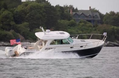 Back Cove 340 Back Cove 340 boat cruising on water, 2026 model, with American flag, surrounded by lush greenery.