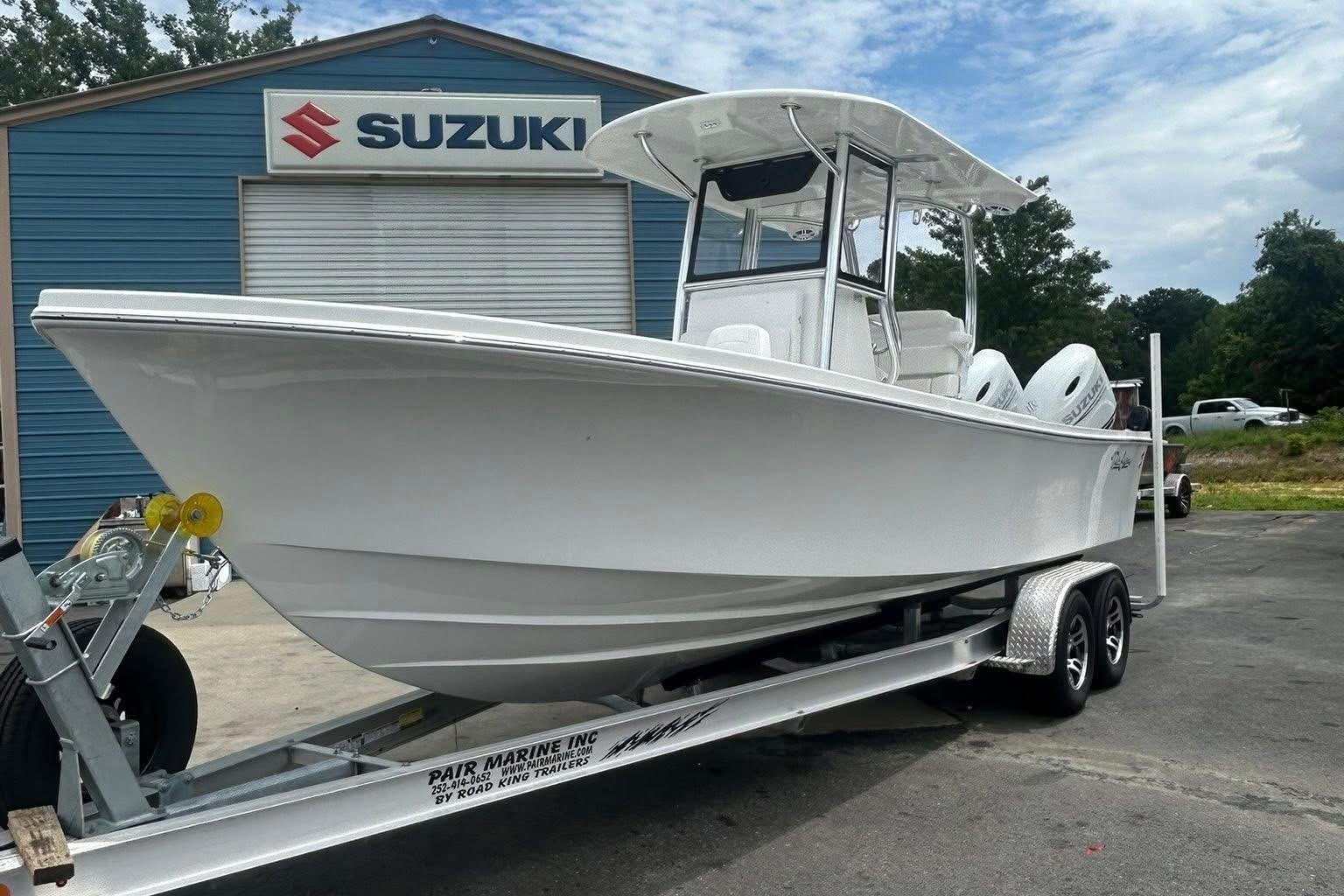 Pair Customs 24 Center Console DV 2026 Pair Customs 24 Center Console DV boat on trailer at Suzuki dealership.