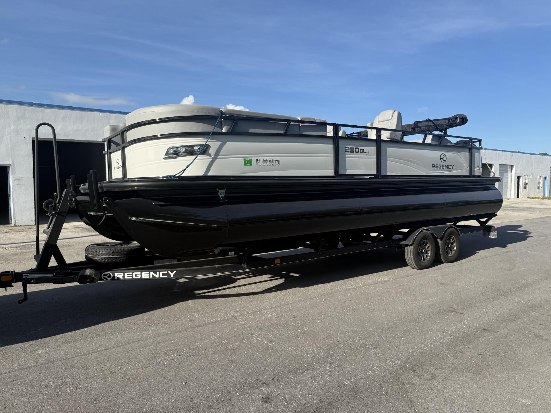 Regency 250 DL3 2024 Regency 250 DL3 pontoon boat on trailer, parked outdoors under clear sky.