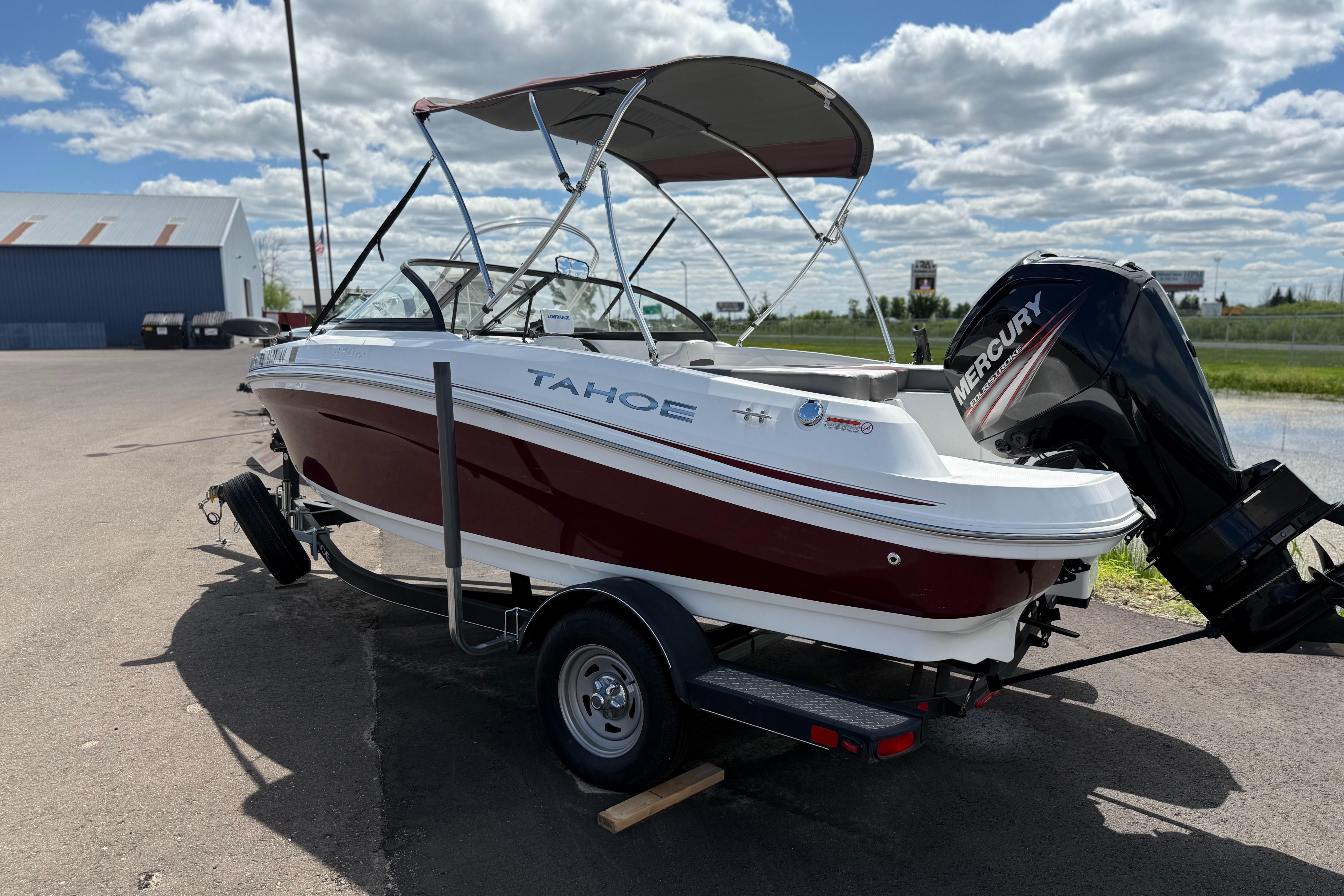 Tahoe 450TF 2018 Tahoe 450TF boat on trailer with Mercury outboard motor, parked outdoors under cloudy sky.
