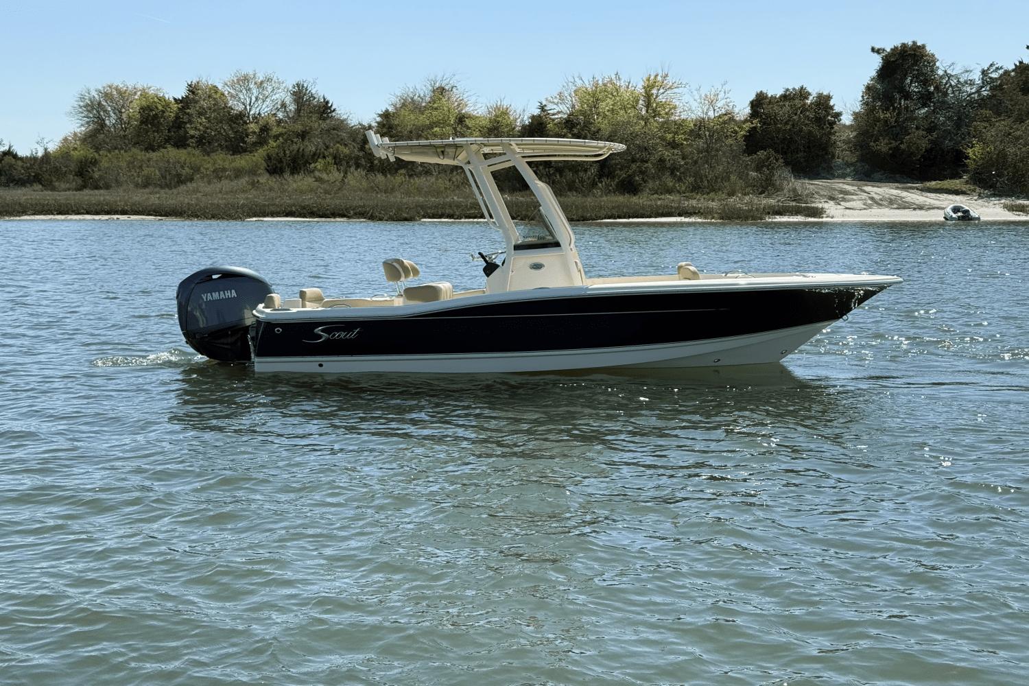Scout 195 Sportfish 2025 Scout 195 Sportfish boat on water with Yamaha engine, near a wooded shoreline.