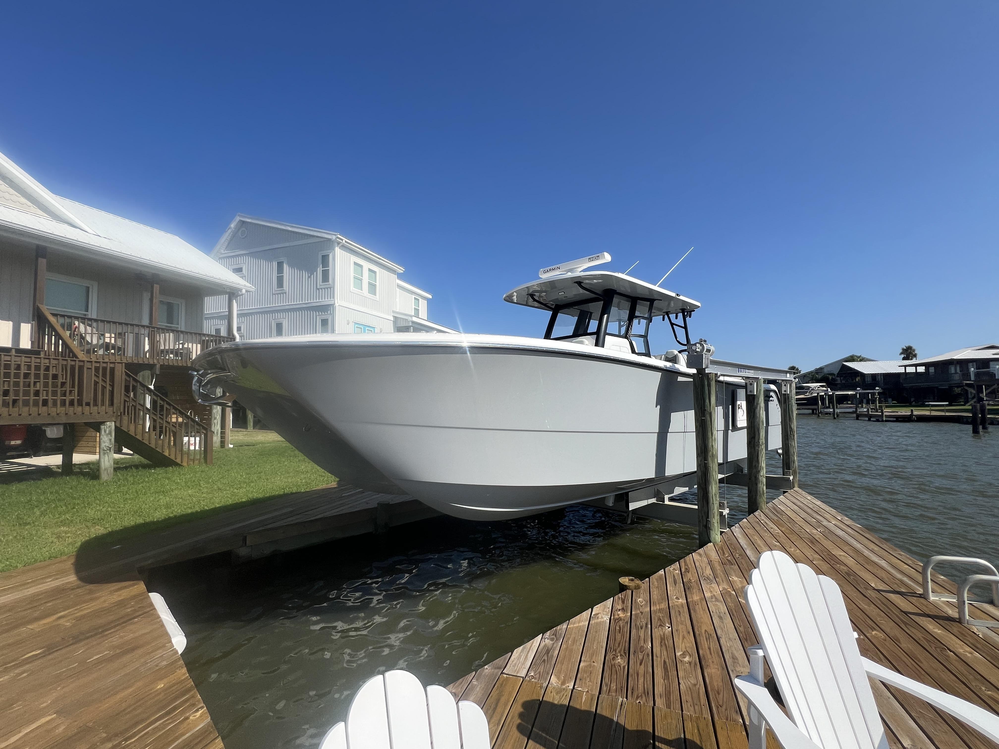 Invincible 35 Catamaran 2024 Invincible 35 Catamaran docked by waterfront homes under clear blue sky.