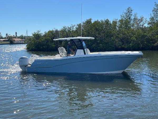 World Cat 280 CC-X 2025 World Cat 280 CC-X boat on calm water, surrounded by trees.