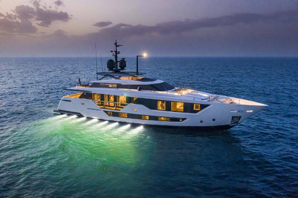 Custom Line 106 Luxurious 2023 Custom Line 106' yacht illuminated on serene ocean at dusk.