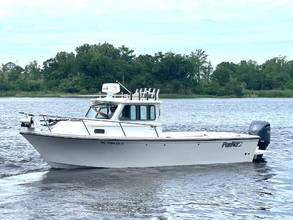 Parker 2320 Sport Cabin 2022 Parker 2320 Sport Cabin boat on calm water, surrounded by lush greenery.