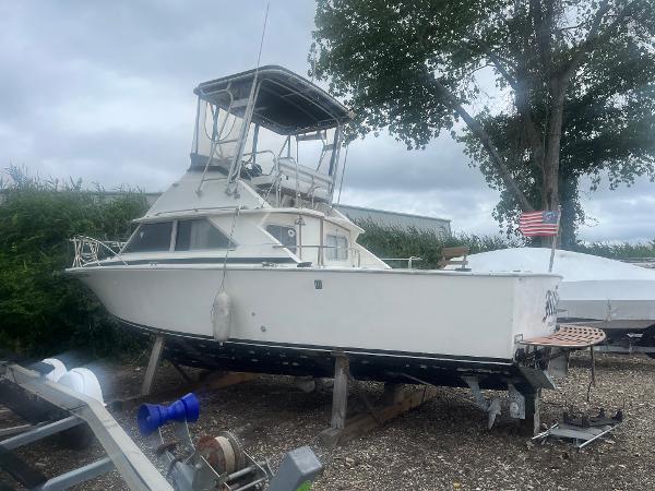 Bertram 28 Flybridge CRUISER 1973 Bertram 28 Flybridge Cruiser on dry dock with American flag nearby.