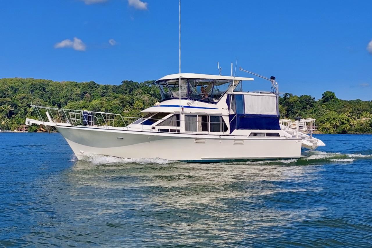 Tollycraft 44 Cockpit Motor Yacht 1986 Tollycraft 44 Cockpit Motor Yacht cruising on a sunny day, surrounded by lush greenery.