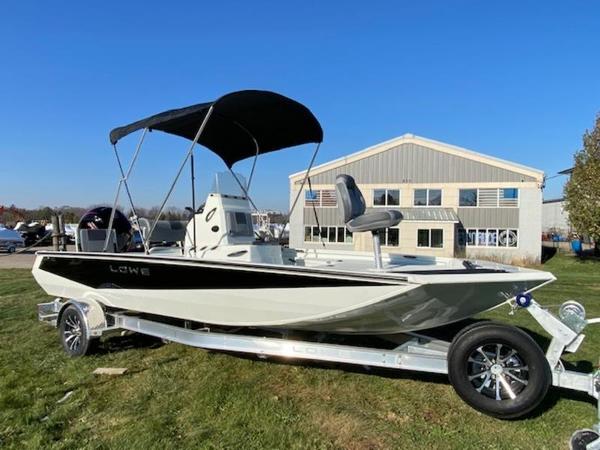 Lowe Bay20 2023 Lowe Bay20 boat on trailer with canopy, parked on grass near a building.