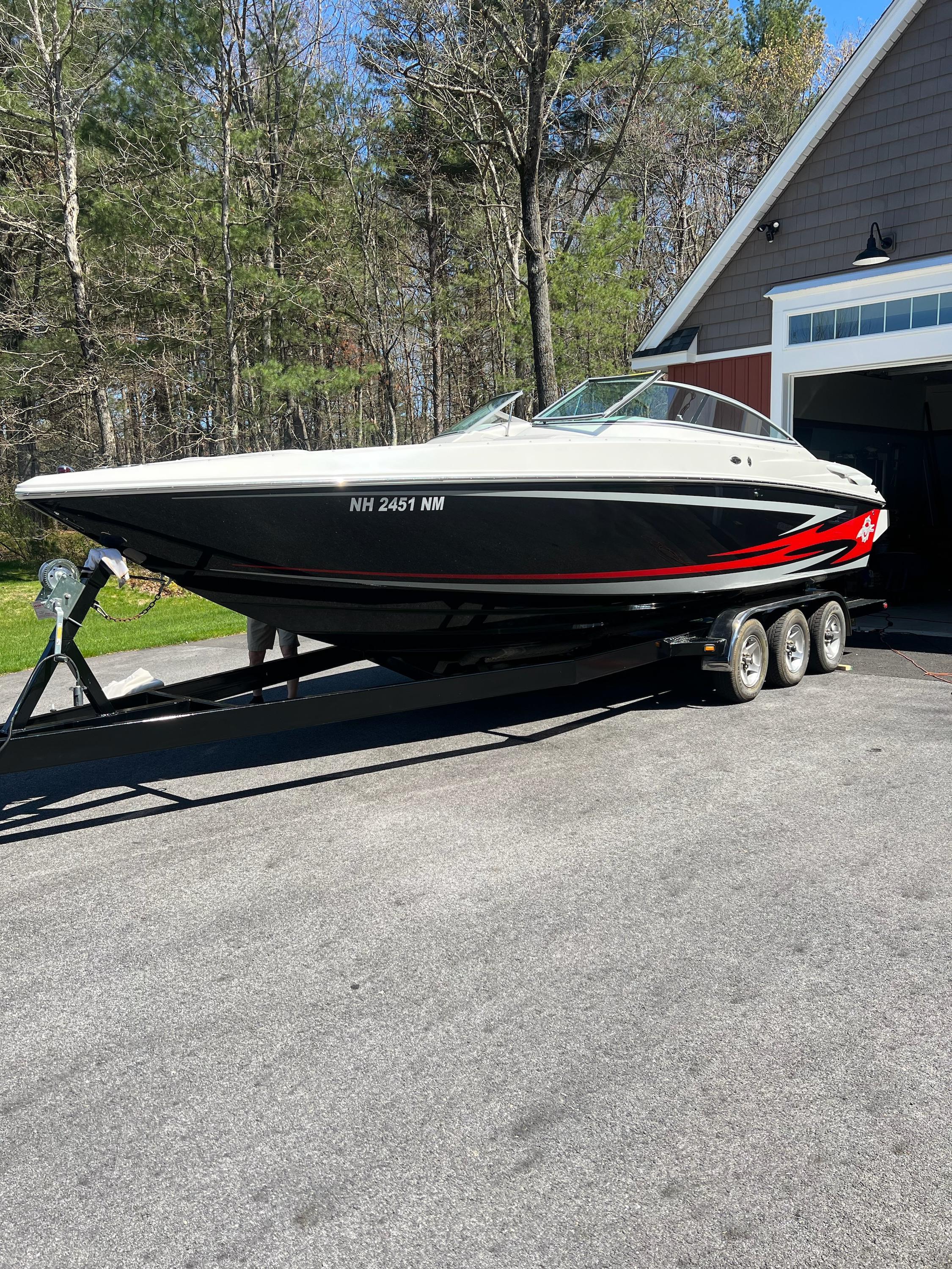 Baja 277 Islander 2009 Baja 277 Islander boat on trailer, parked outdoors near a garage.