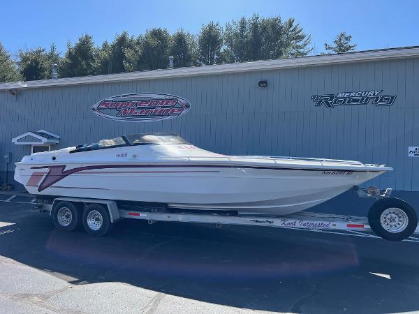 Velocity 260 1998 Velocity 260 speedboat on trailer, parked outside a building with racing logos.