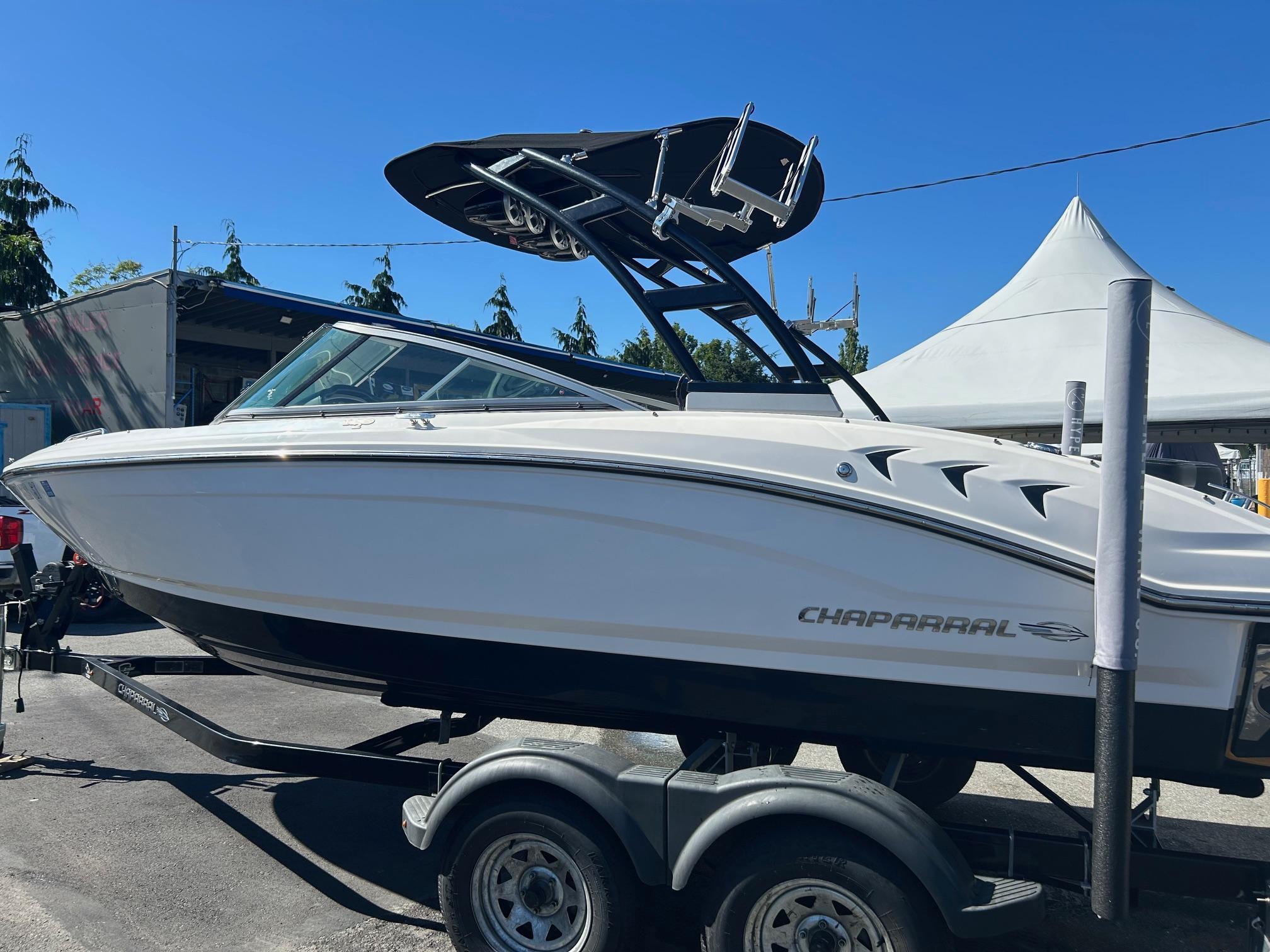 Chaparral 21 H2O Surf 2018 Chaparral 21 H2O Surf boat on trailer, parked outdoors under clear blue sky.