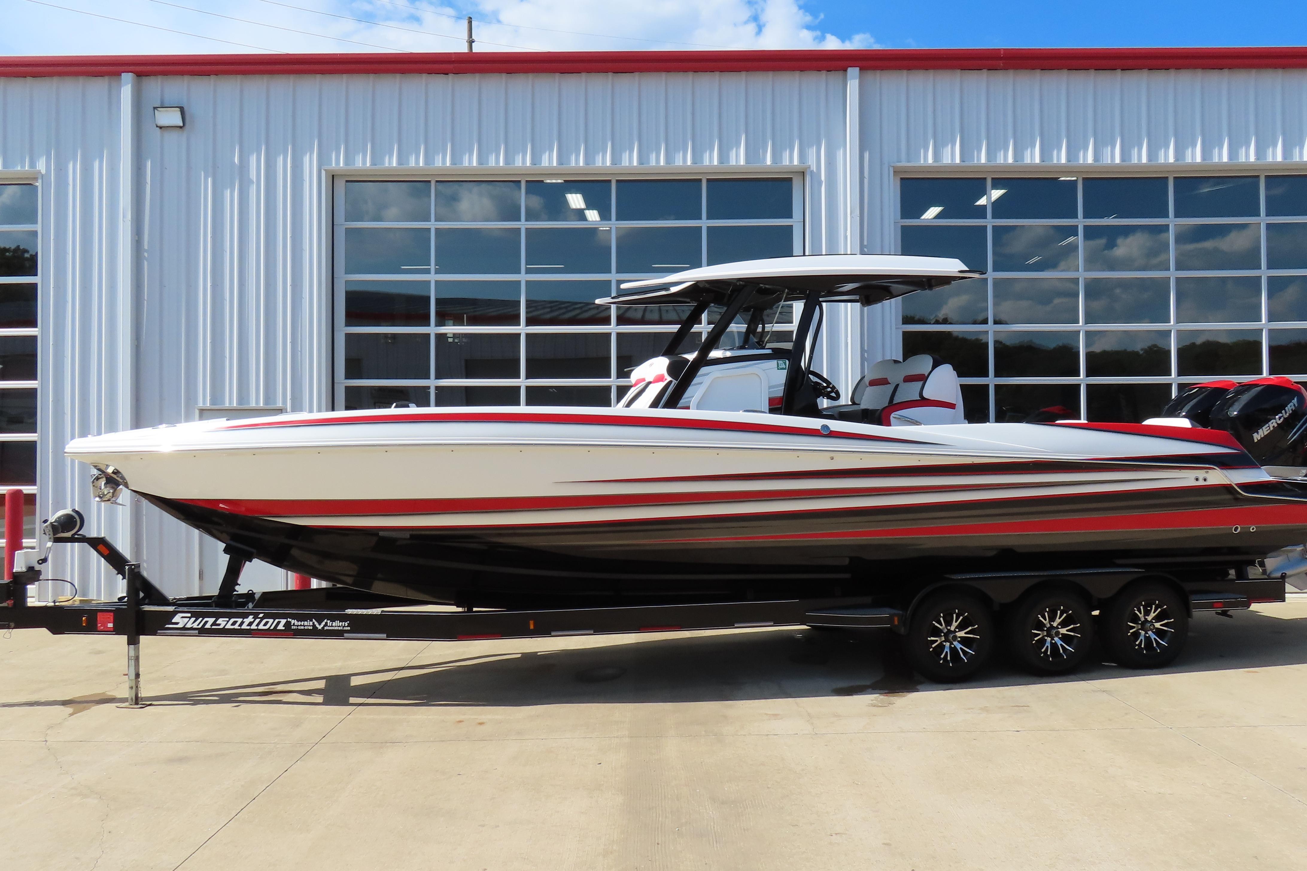 Sunsation 32CCX 2022 Sunsation 32CCX boat on trailer, parked outside a garage.