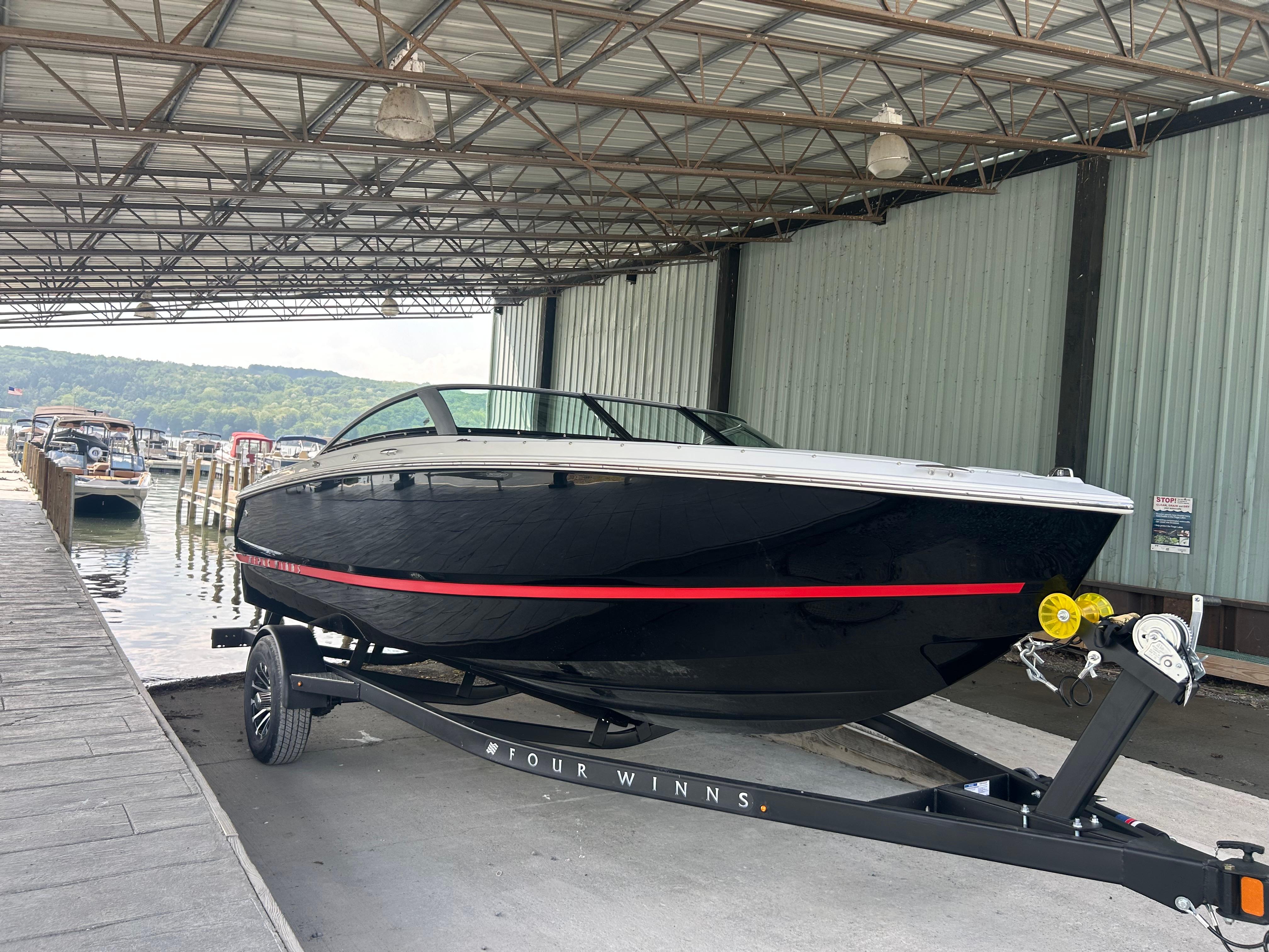 Four Winns H1 Freedom 2026 Four Winns H1 Freedom boat on trailer in covered dock area.