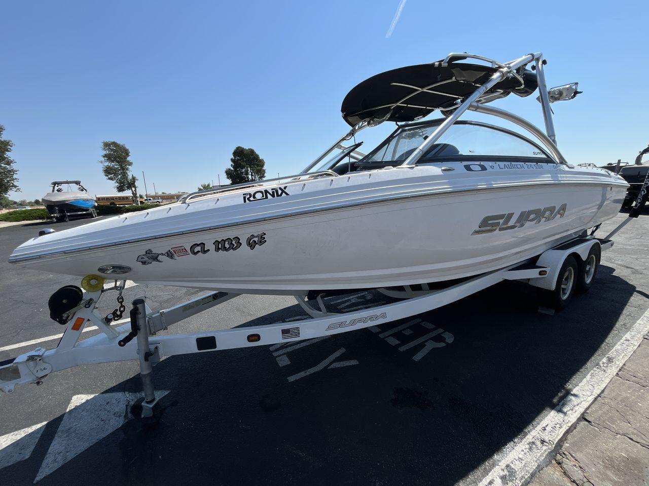 Supra Launch 24 SSV 2009 Supra Launch 24 SSV boat on trailer, parked outdoors under clear sky.