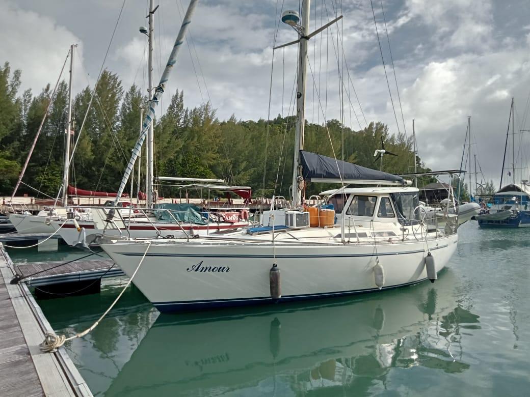 Moody 376 1988 Moody 376 sailboat docked in a marina, surrounded by calm water and trees.