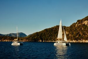 Bali CATSPACE Two Bali CATSPACE catamarans sailing near a scenic coastline, 2023 model.