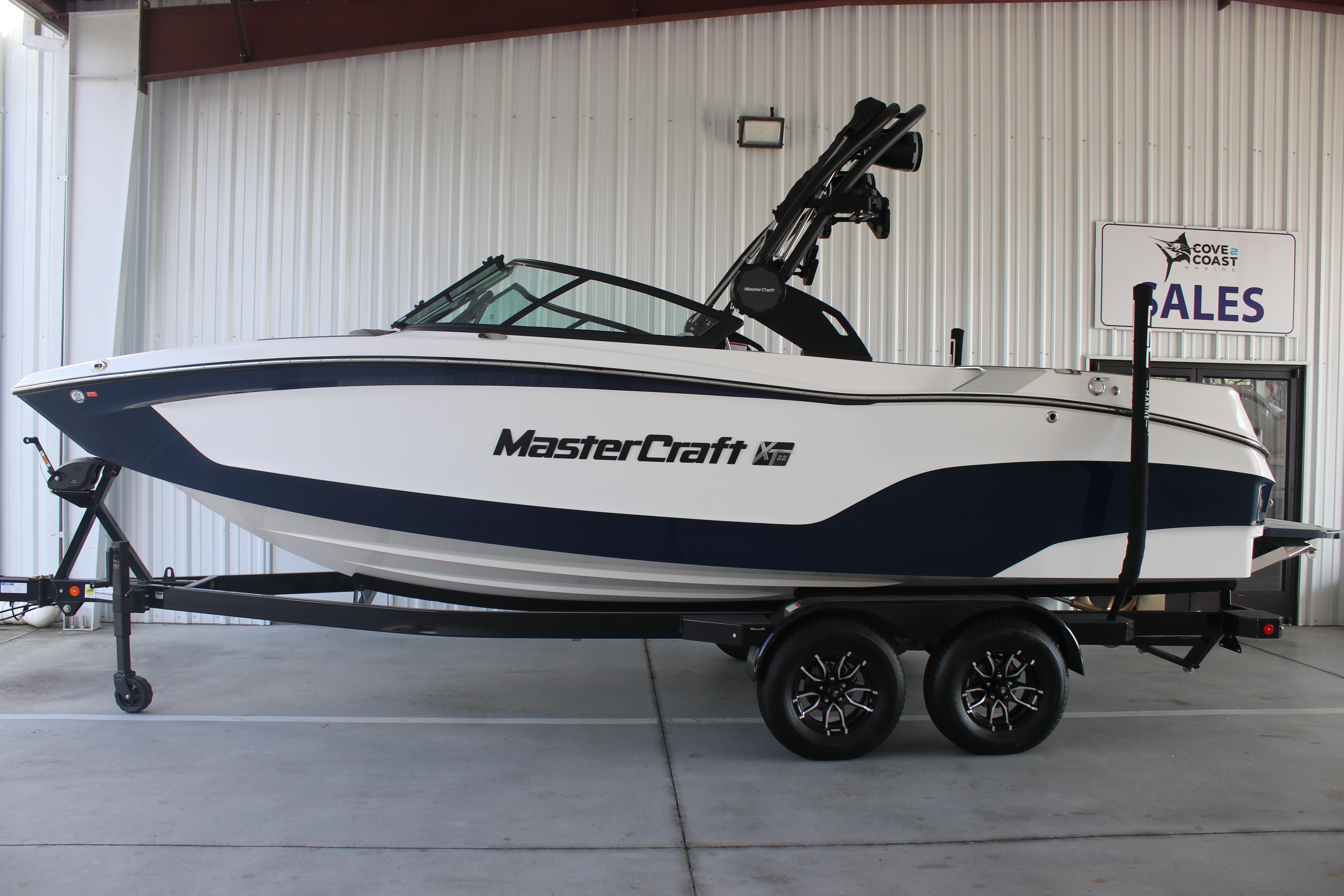 MasterCraft XT22 2025 MasterCraft XT22 boat on trailer in showroom, side view.
