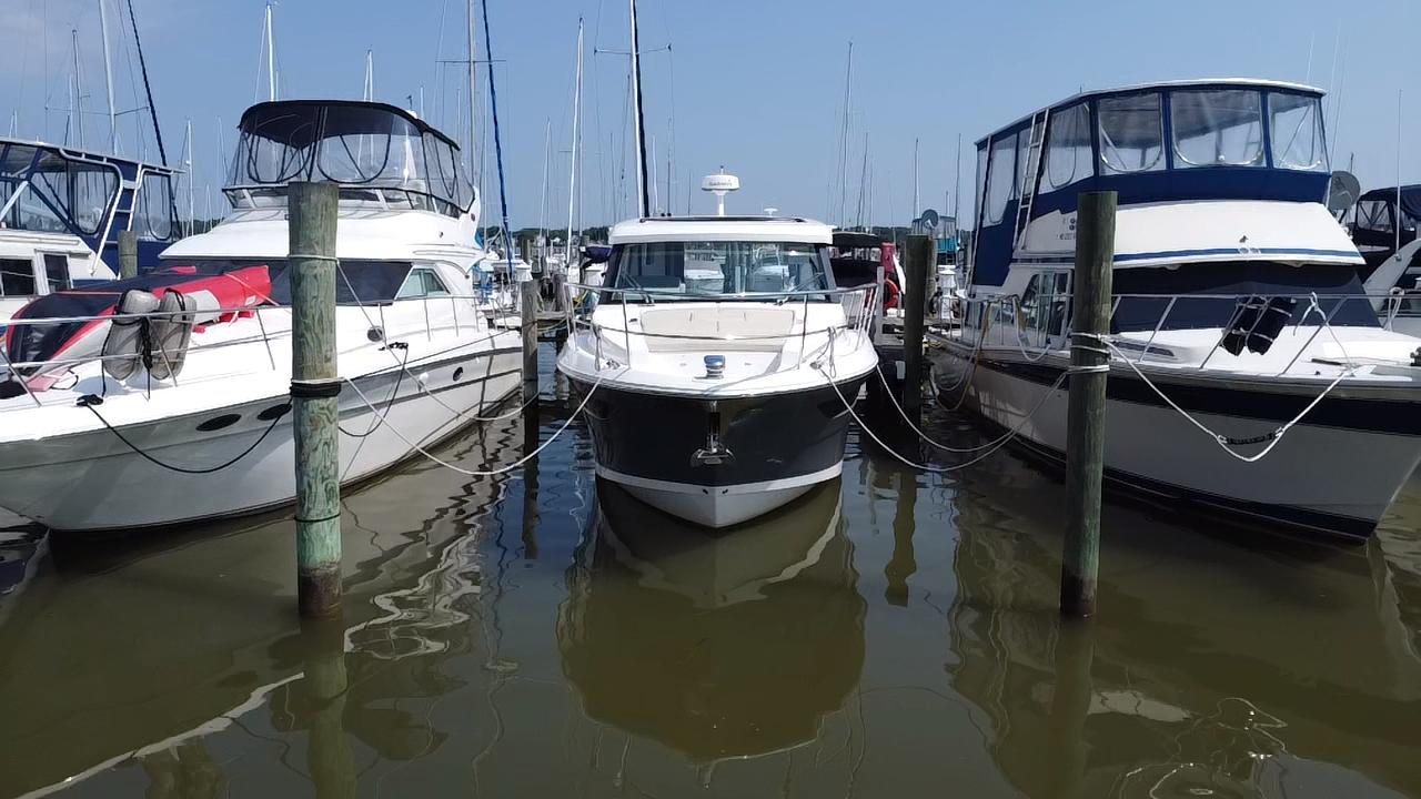 Regal 38 Grande Coupe 2020 Regal 38 Grande Coupe docked between two boats at a marina.