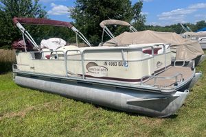 Lowe Trinidad 180 2001 Lowe Trinidad 180 pontoon boat on grass, under clear blue sky.