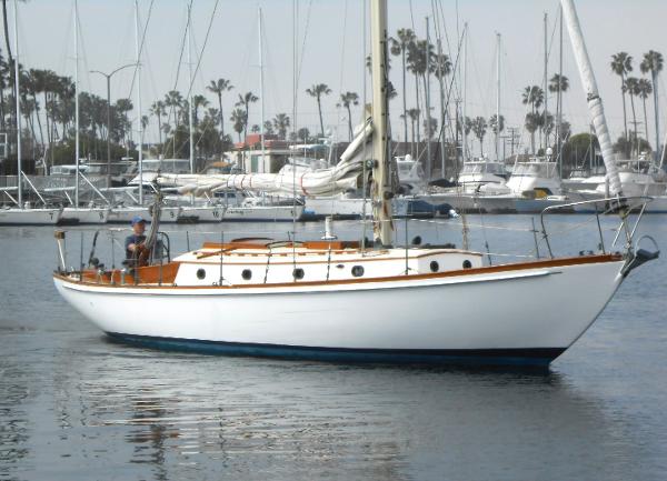 Custom McIntosh Merrywing Vintage 1962 Custom McIntosh Merrywing sailboat in marina, surrounded by palm trees and yachts.
