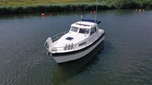 Hardy Mariner 25 1999 Hardy Mariner boat on calm water with buoys and grassy shoreline.