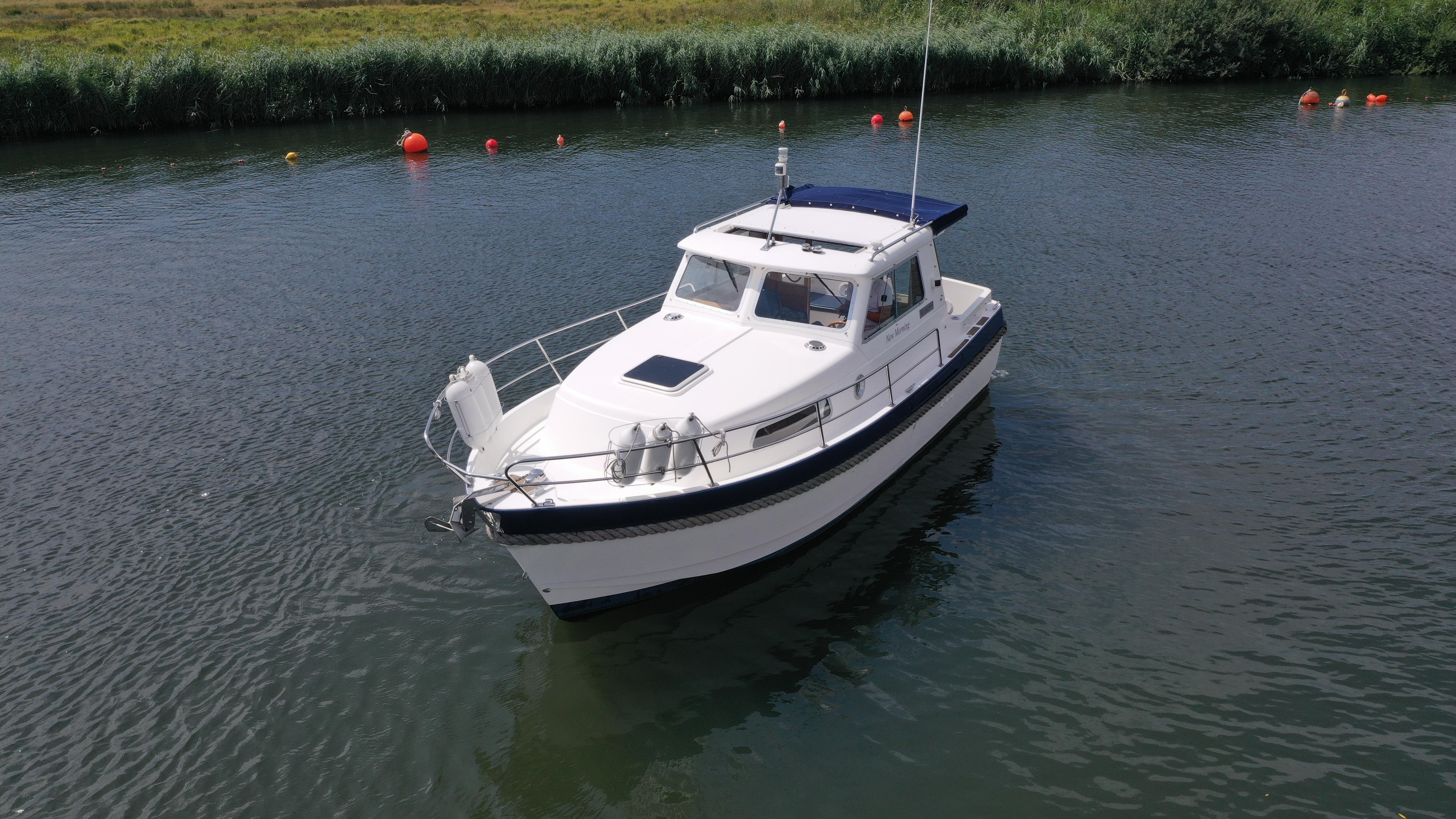 Hardy Mariner 25 1999 Hardy Mariner boat on calm water with buoys and grassy shoreline.