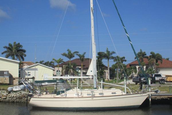 Island Packet 380 1999 Island Packet 380 sailboat docked near palm trees and houses.