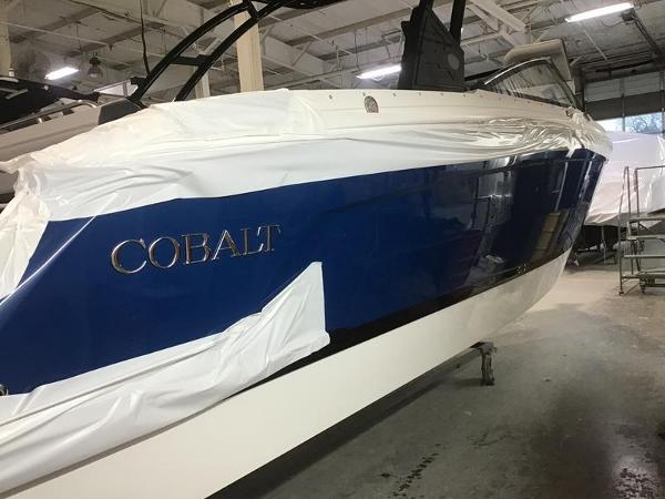 Cobalt R8 2025 Cobalt R8 boat in a workshop, partially covered, showcasing sleek blue and white design.
